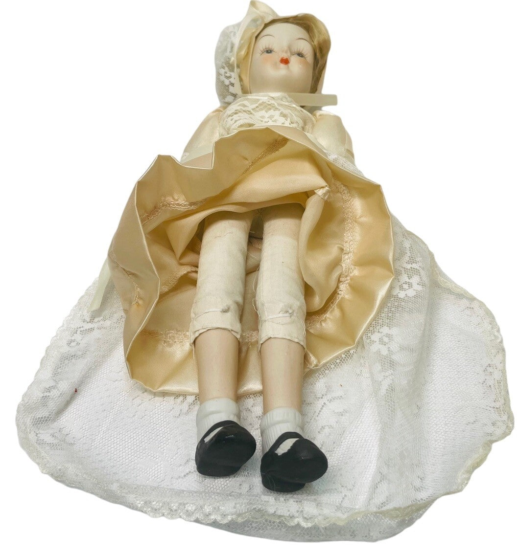 PORCELAIN DOLL 14" WEARING CREAM LACE SATIN GOWN W/MATCHING LACE BONNET.