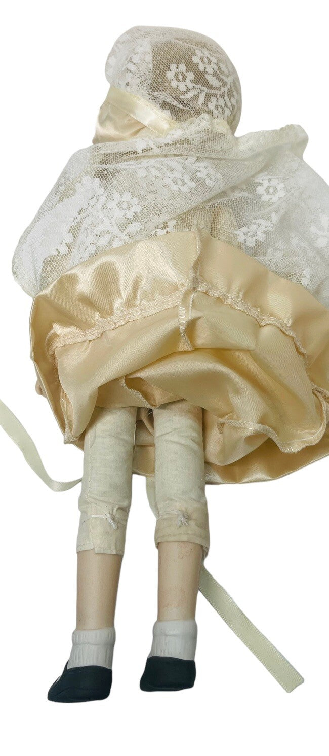 PORCELAIN DOLL 14" WEARING CREAM LACE SATIN GOWN W/MATCHING LACE BONNET.